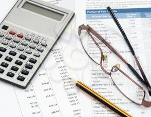 calculator, glasses, pencil on top of tax documents